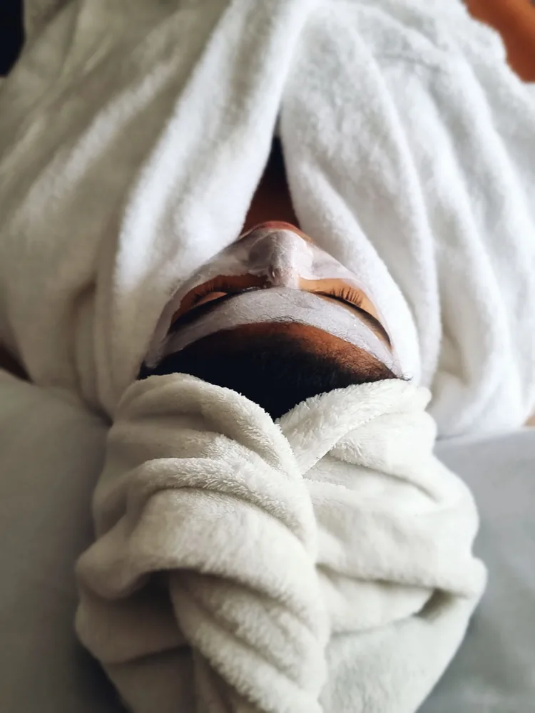 Femme détendue avec un masque pendant un soin du visage en institut